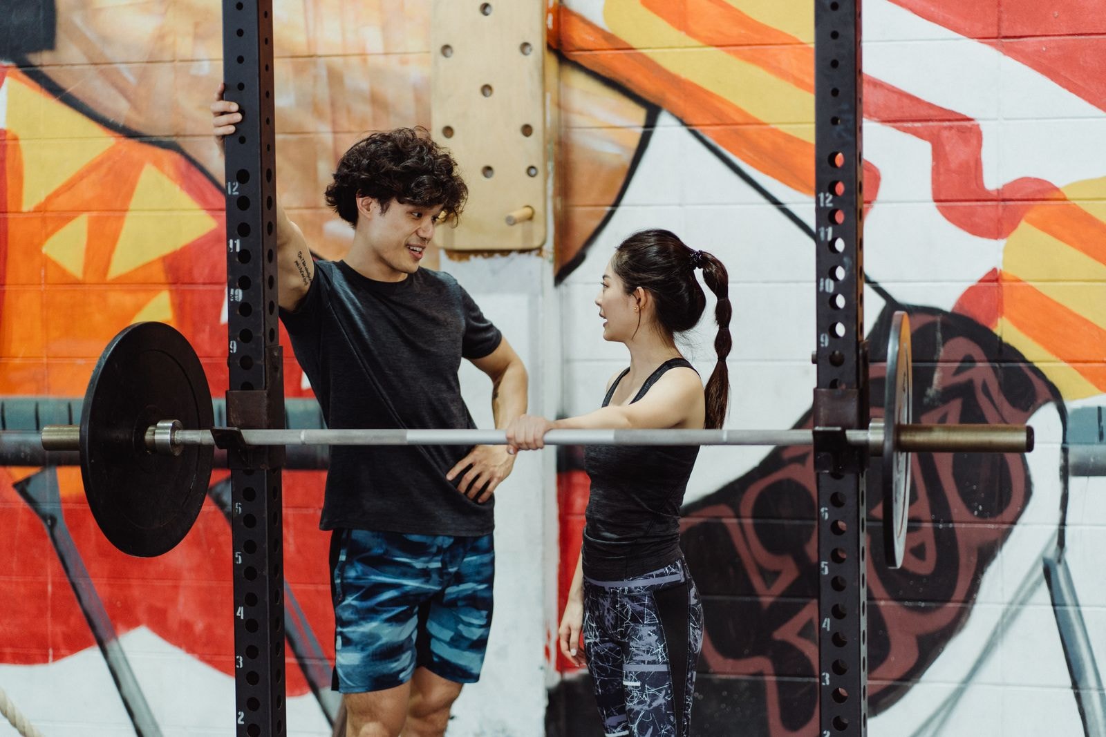 A coach and a client talking between sets at the rack