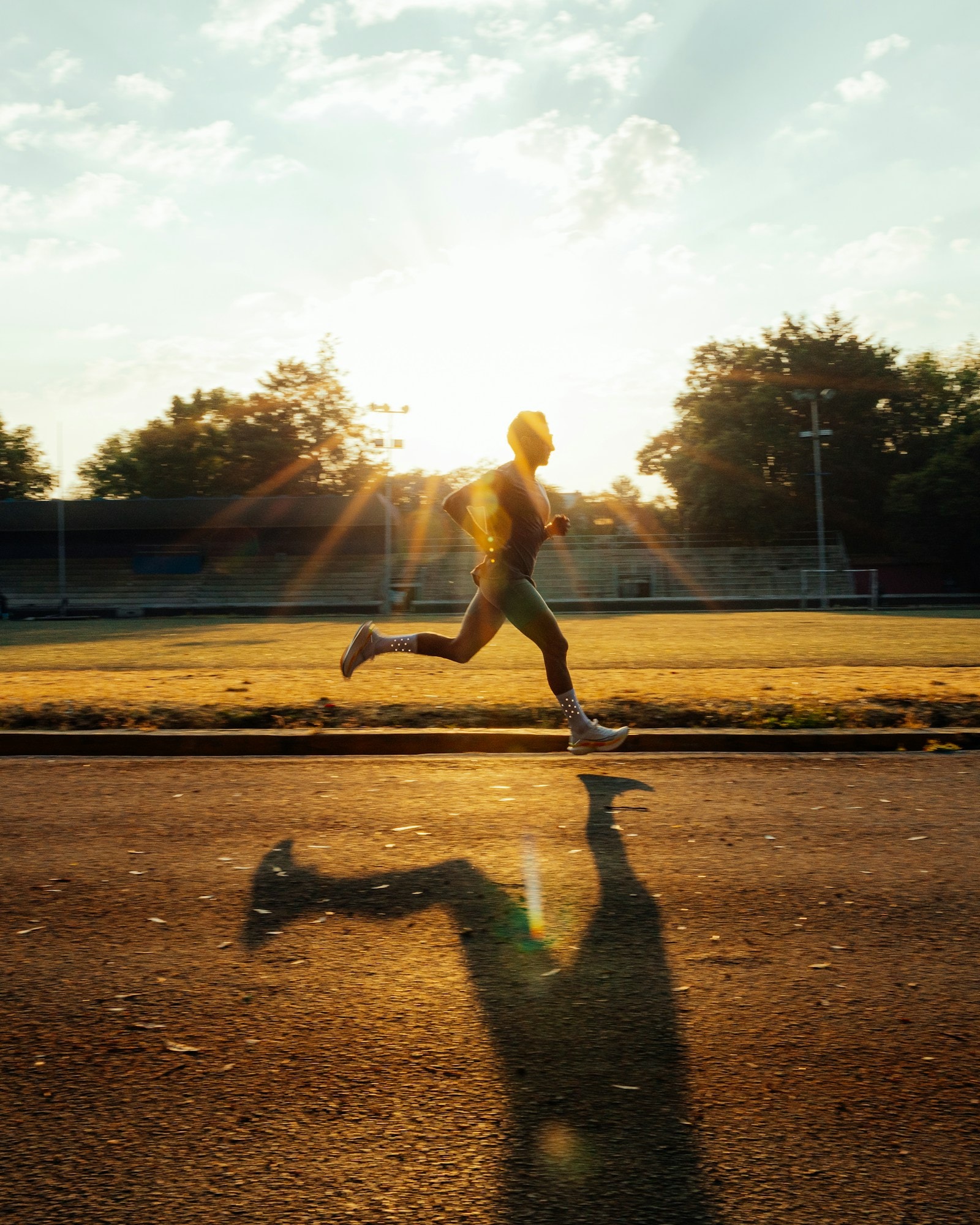 A runner on a track at sunrise, a long shadow behind