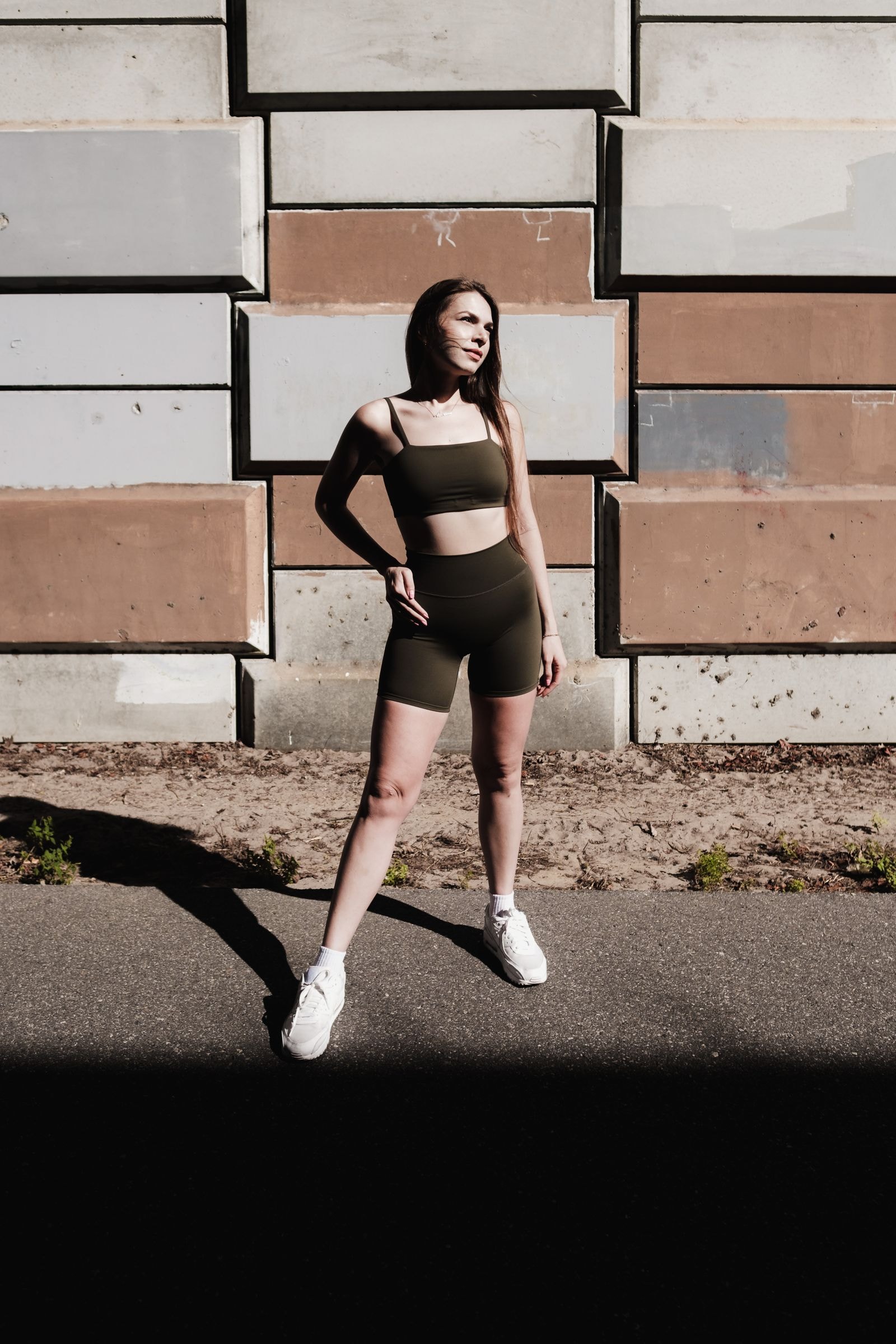 A woman in brown training wear against a stone wall