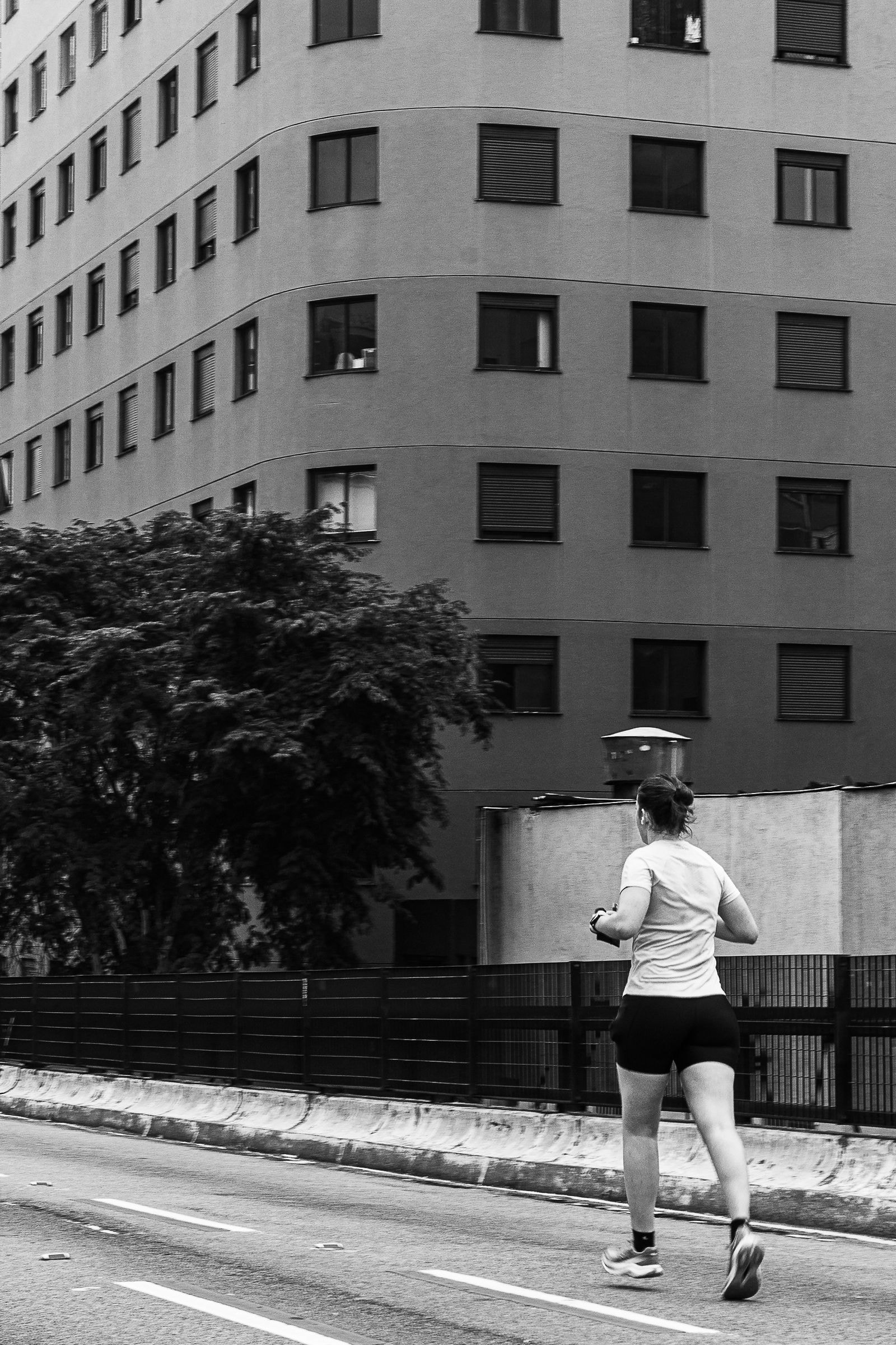 A runner passing an apartment block, black and white