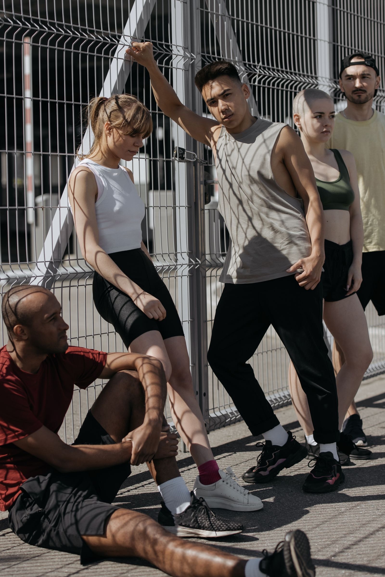 A running crew resting against a fence after a session