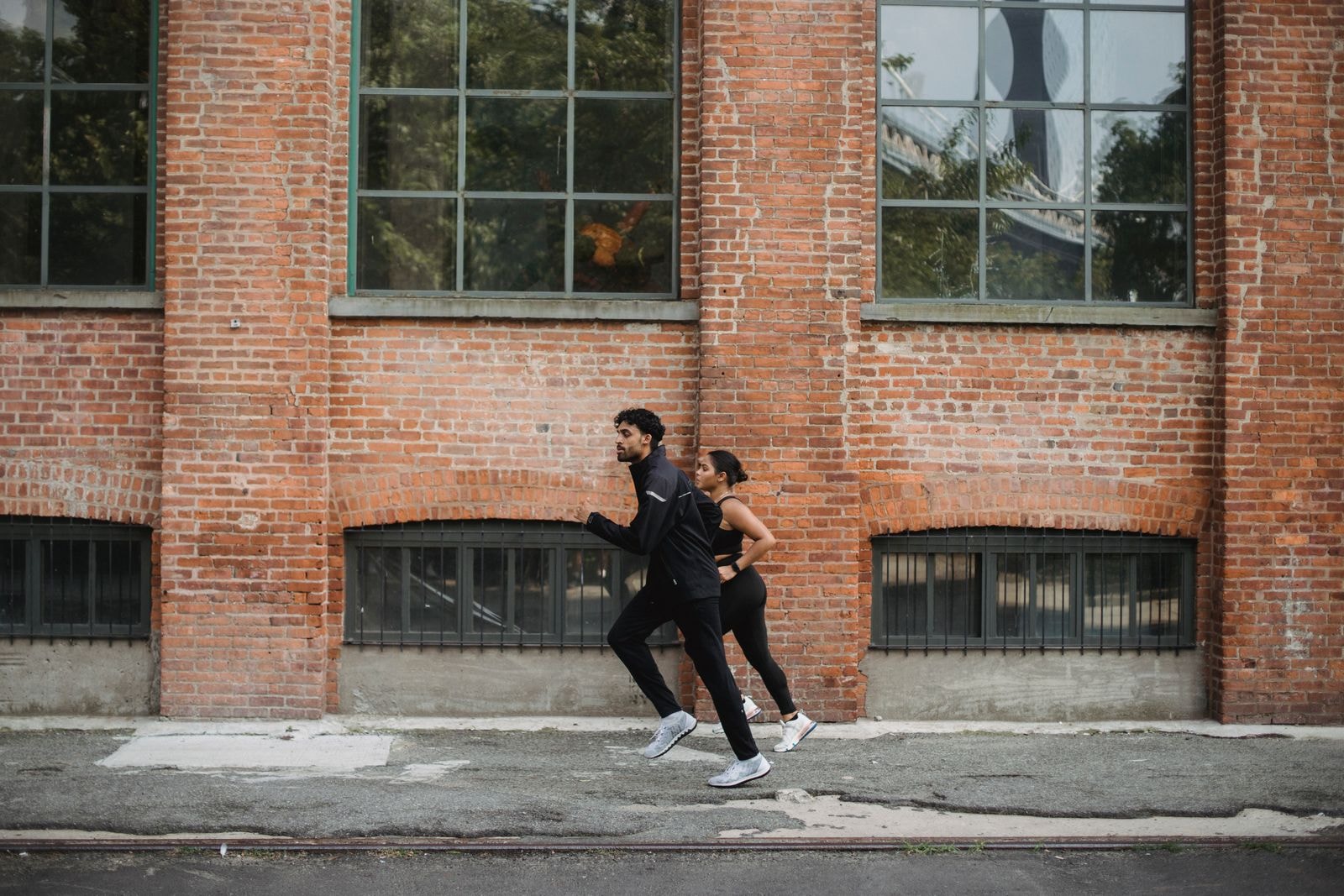 Two runners passing a brick warehouse