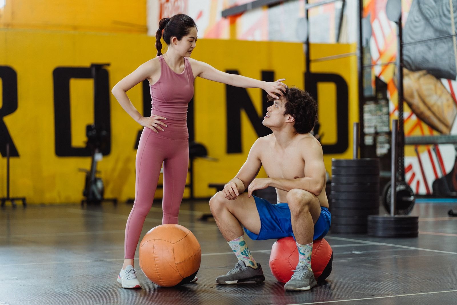 Two people catching their breath on medicine balls
