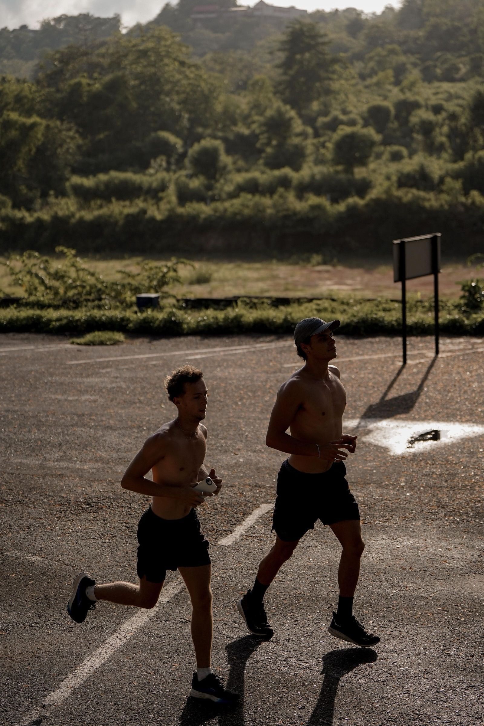 Two runners side by side on an empty lot in low morning sun
