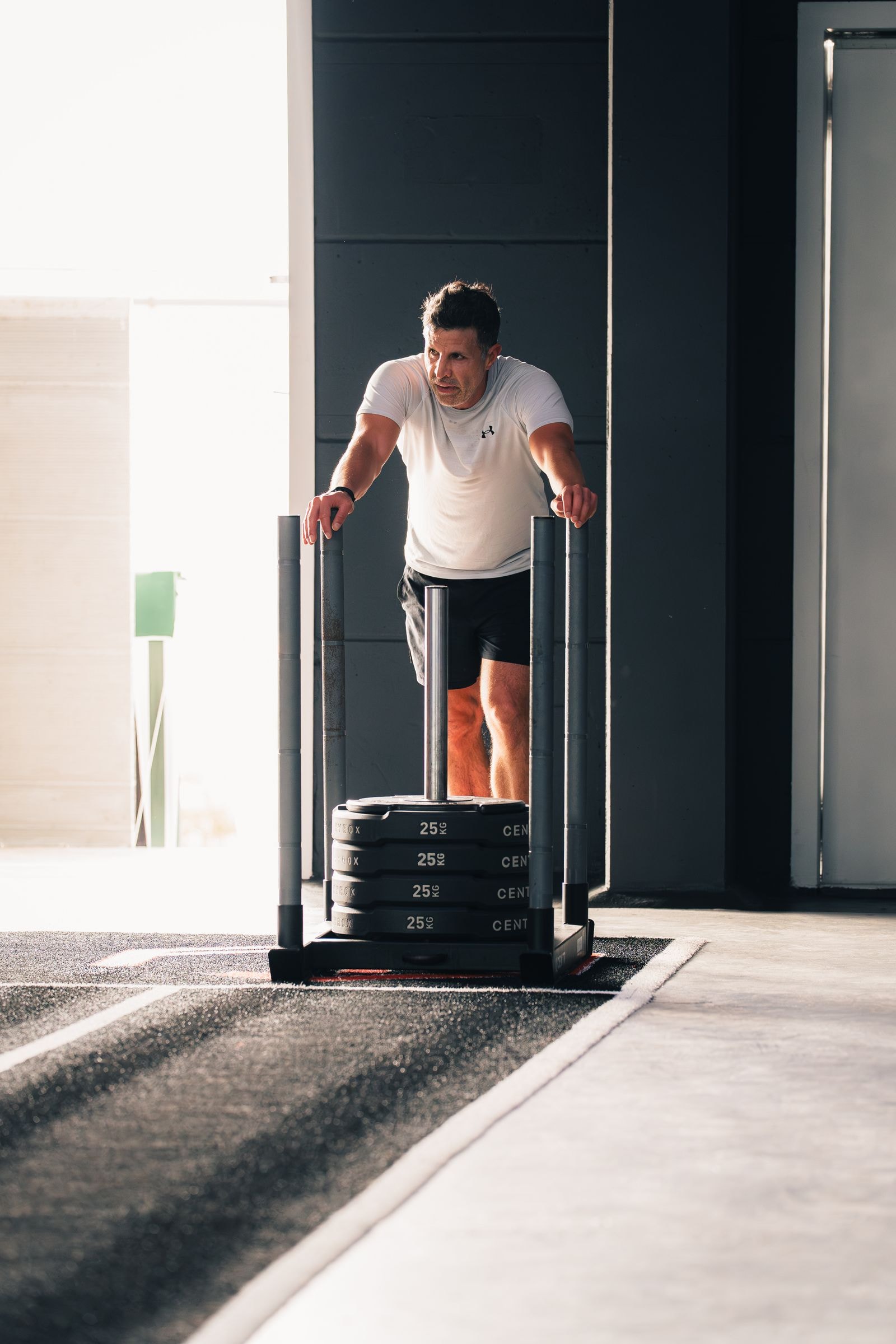 An athlete pushing a loaded sled in a bright gym