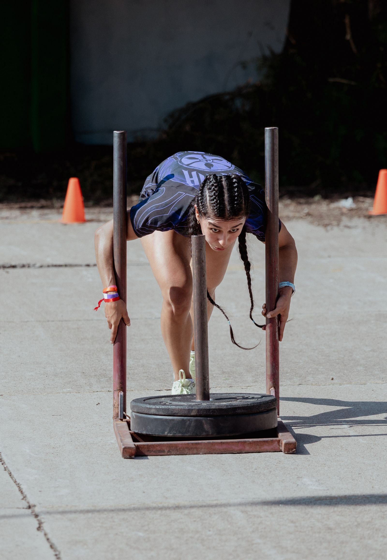An athlete driving a loaded sled across the floor