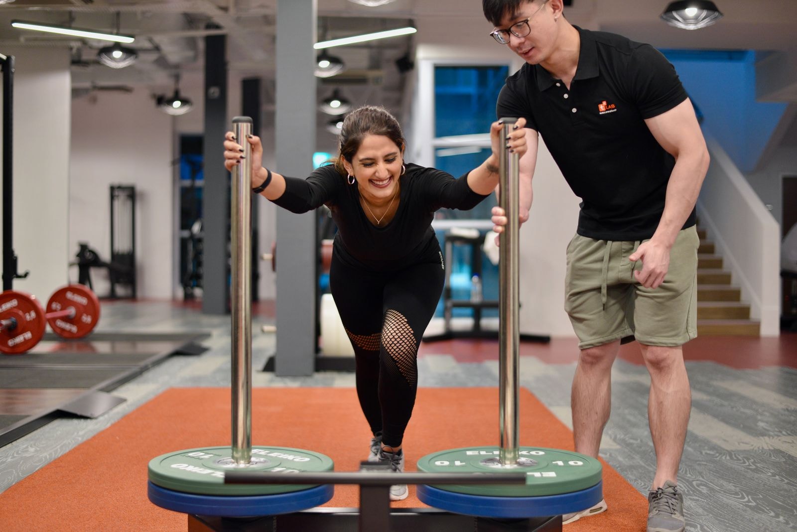 A coach cueing a client through a sled push