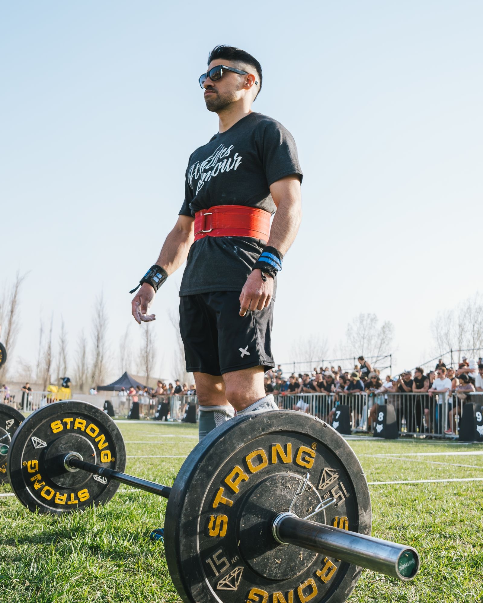 A lifter in a belt standing over a loaded deadlift bar