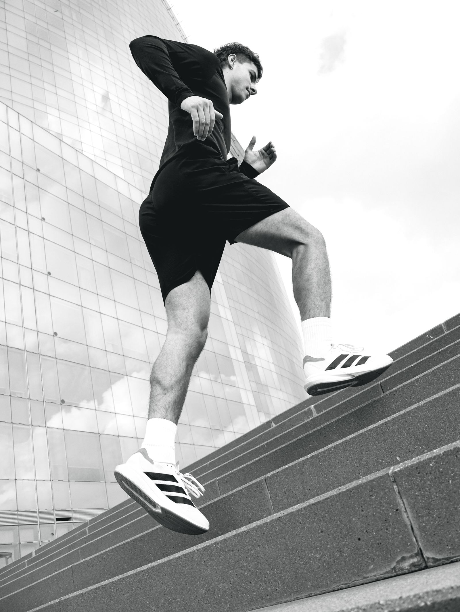 A runner climbing concrete steps at pace, black and white